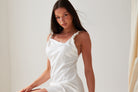 A person with long brown hair is wearing the Sarvin A-Line Mini Slip Dress, posing indoors against a simple light background.