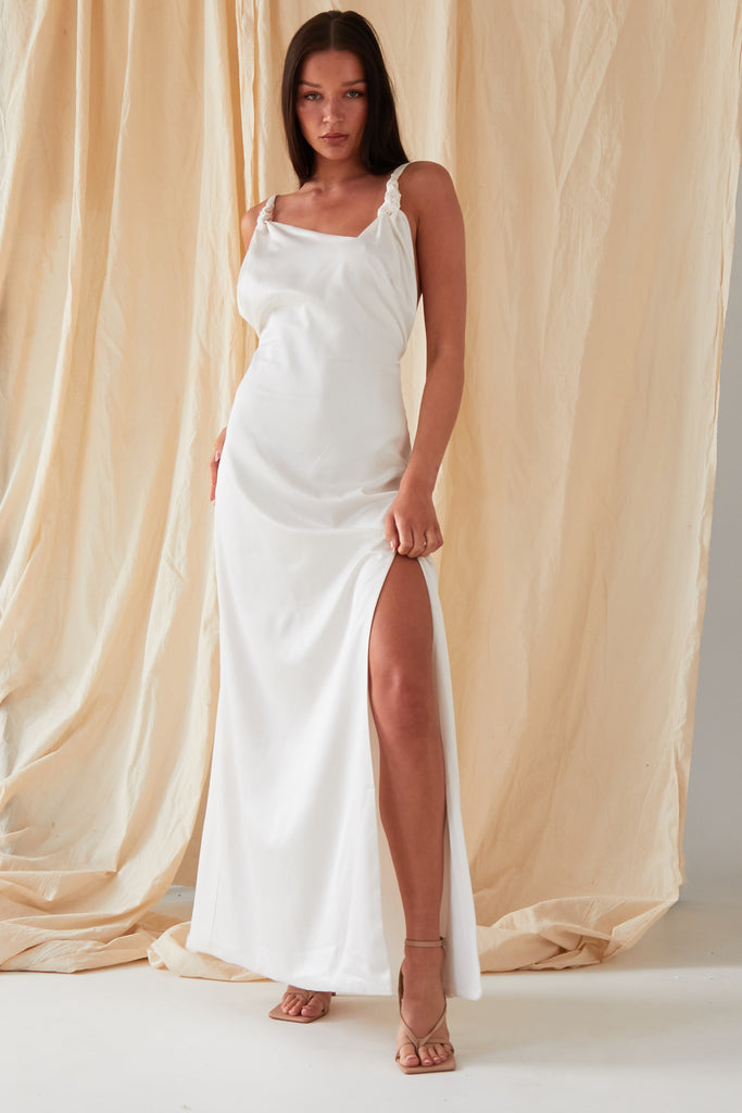 The model is wearing a Sarvin Asymmetric White Maxi Dress with a slit.