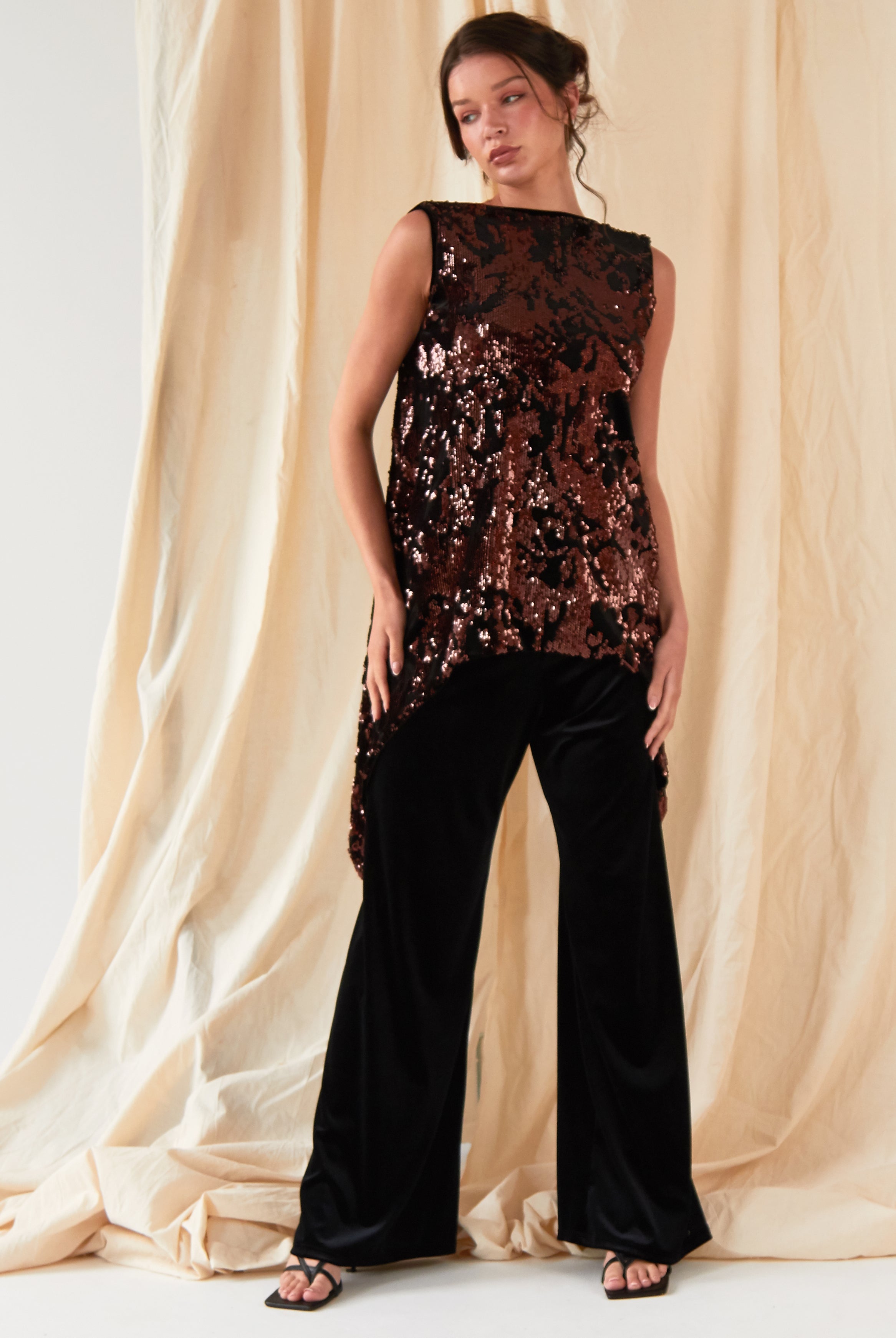 The model is wearing a Sarvin sequin top and Sarvin Wide Leg Velvet Trousers.