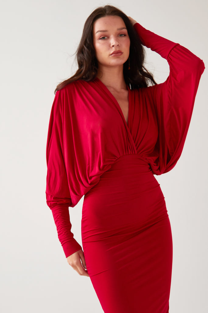 The model is wearing a Sarvin Red Batwing Dress with long sleeves.