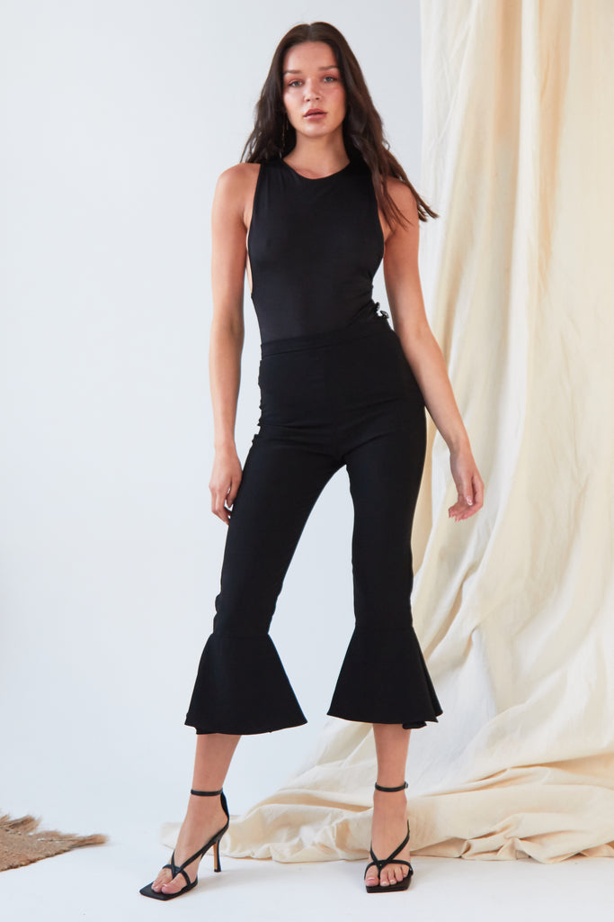 The model is wearing a black crop top and Sarvin flared pants.