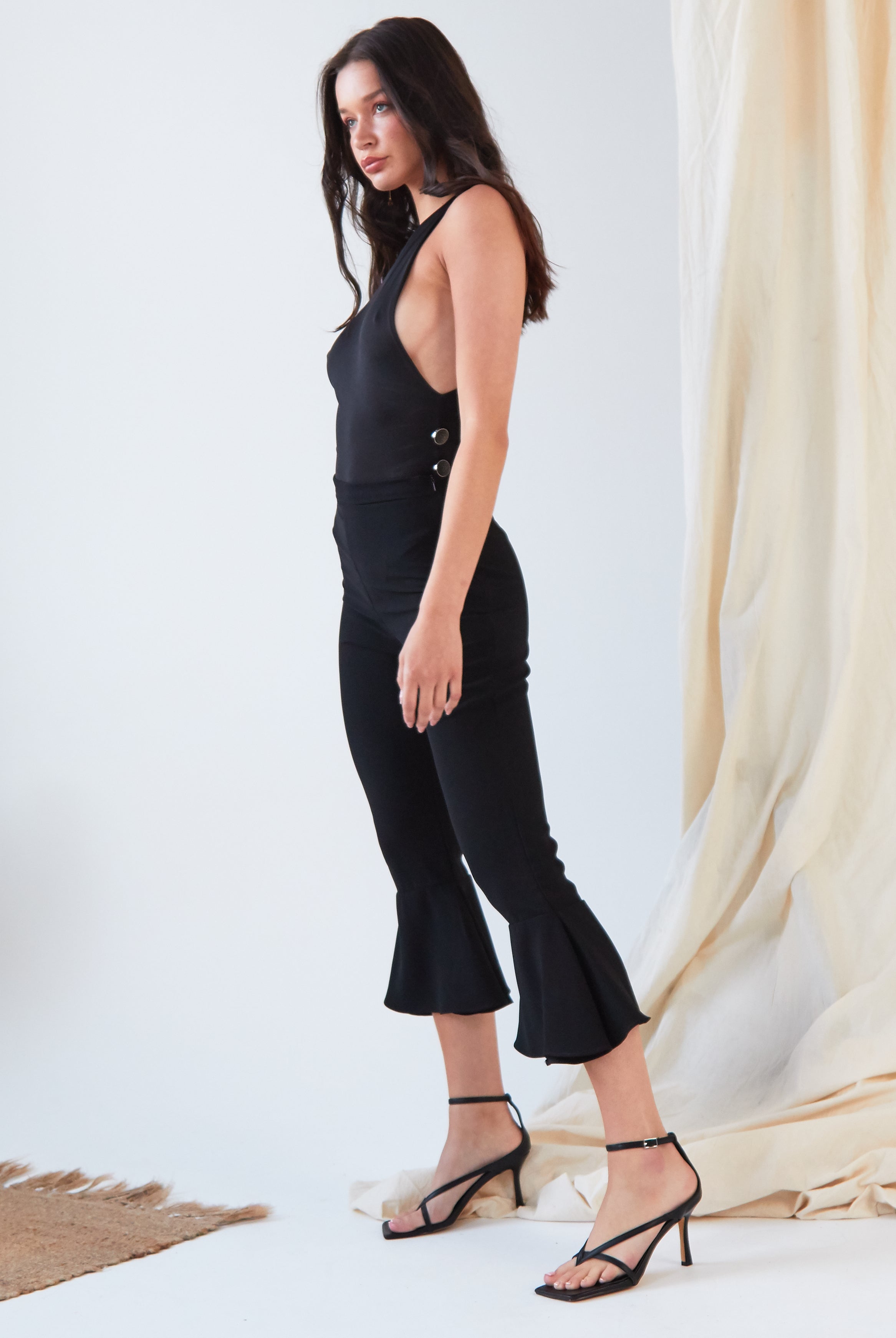 The model is wearing Sarvin's Black Frill Hem Trousers and heels.