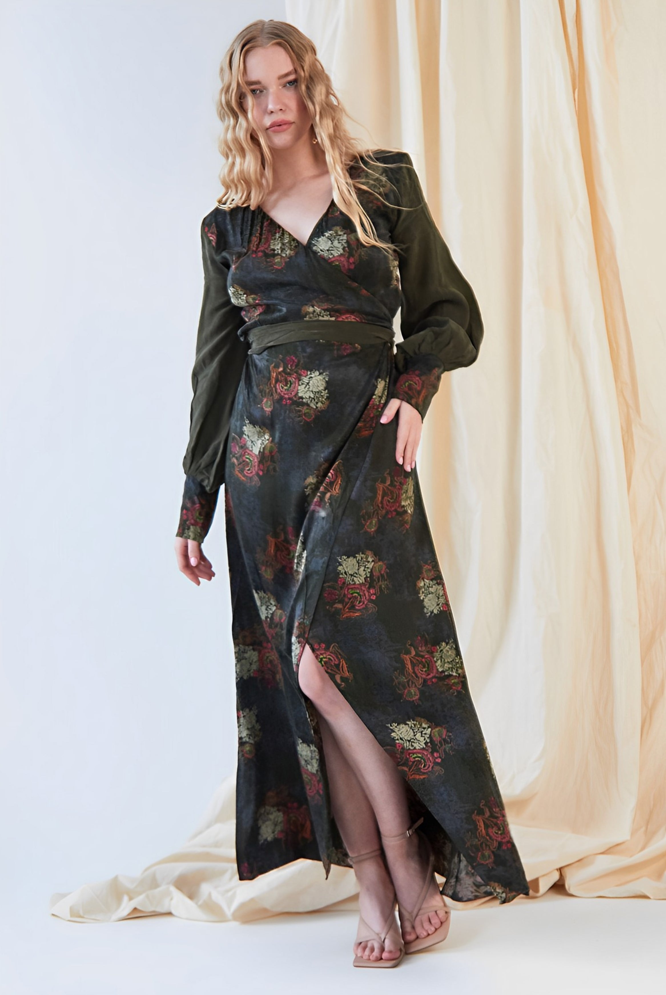 A woman in a Sarvin long sleeve wrap dress standing in front of a curtain.