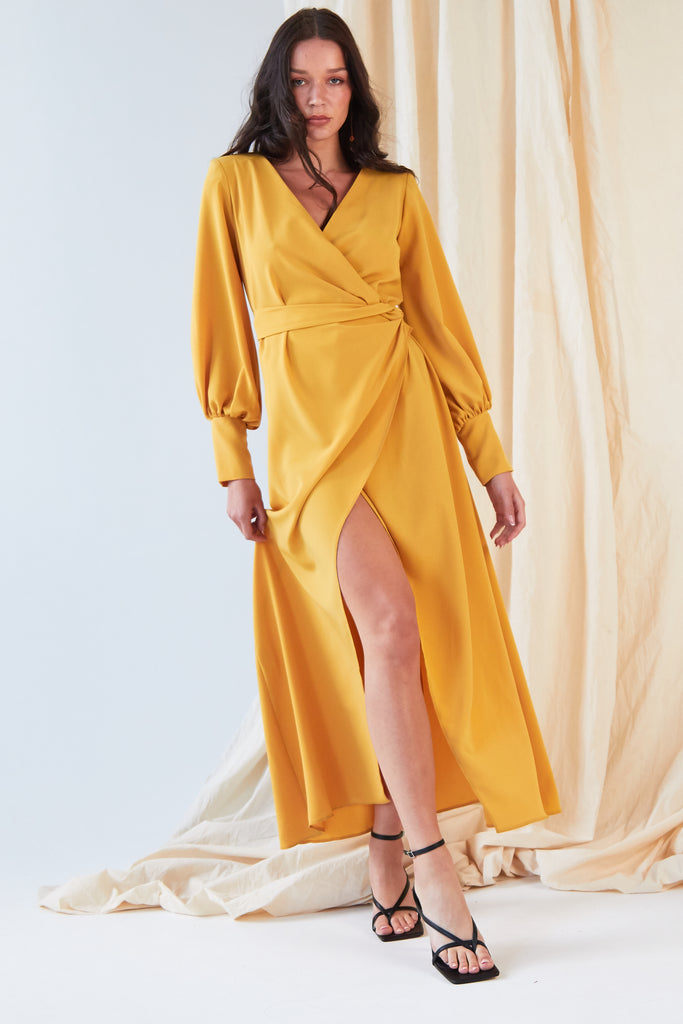 The model is wearing a Sarvin Mustard Wrap Dress with slits.