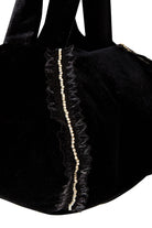 Close-up of Sarvin’s Diamond-Trimmed Lace Velvet Pouch Bag—an elegant black velvet evening accessory with lace trim, diamond-like beading along the edge, and soft black handles.