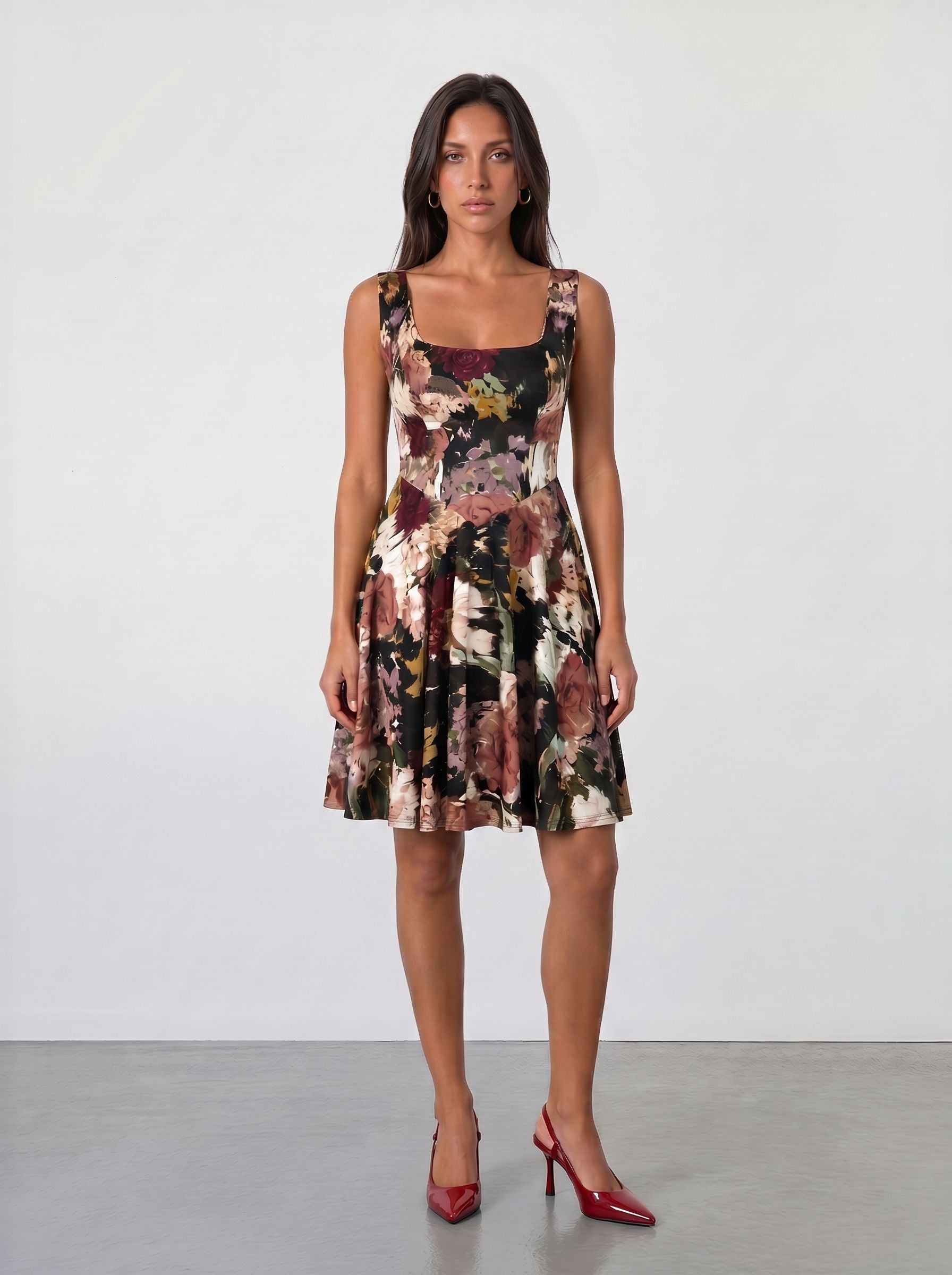 A woman faces forward against a white background, wearing the Sarvin Golha Floral Corset Dress with a flared skater skirt and red pointed-toe heels, her arms relaxed at her sides.