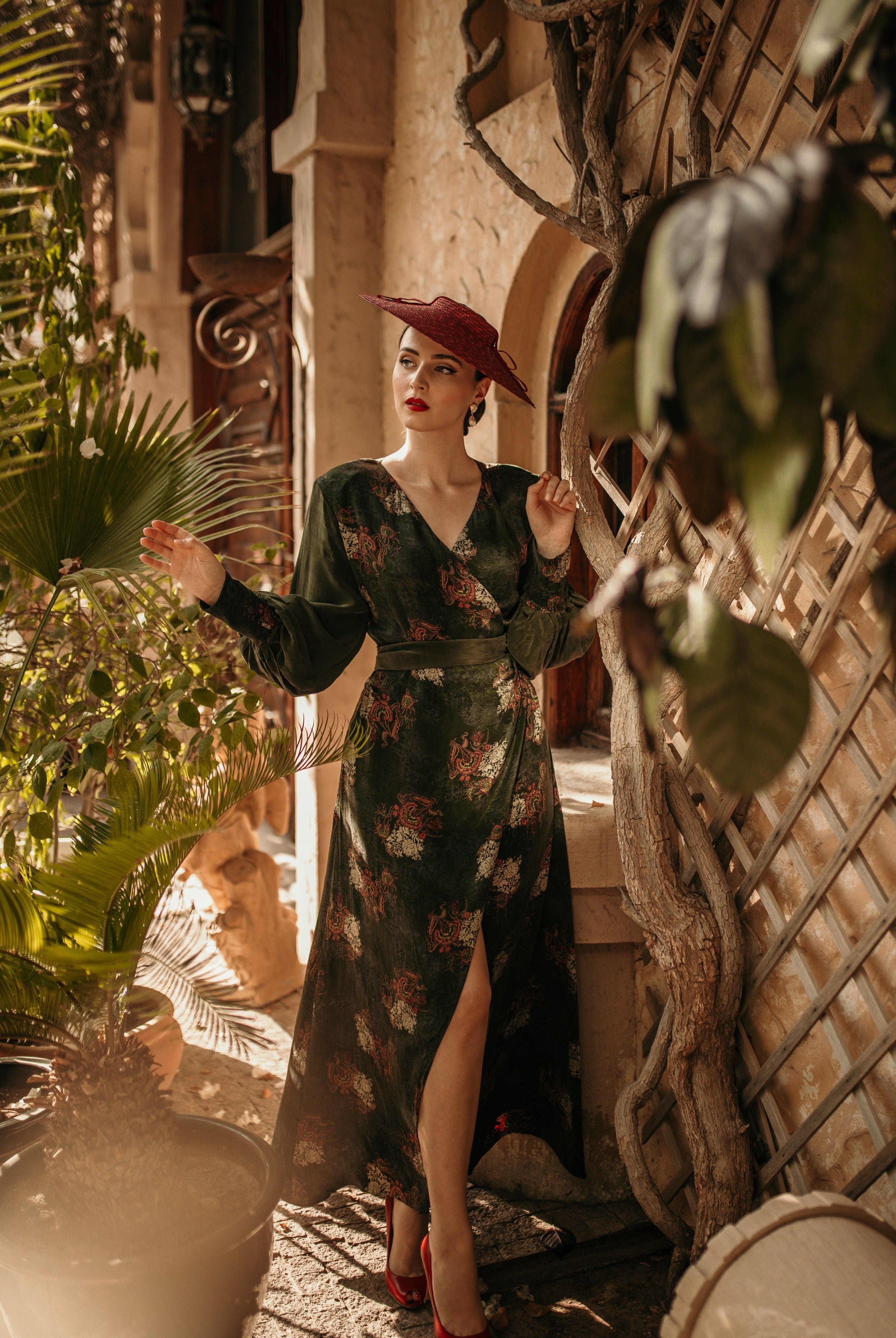 a woman in a Sarvin Long Sleeve Wrap Dress standing in front of a potted plant.