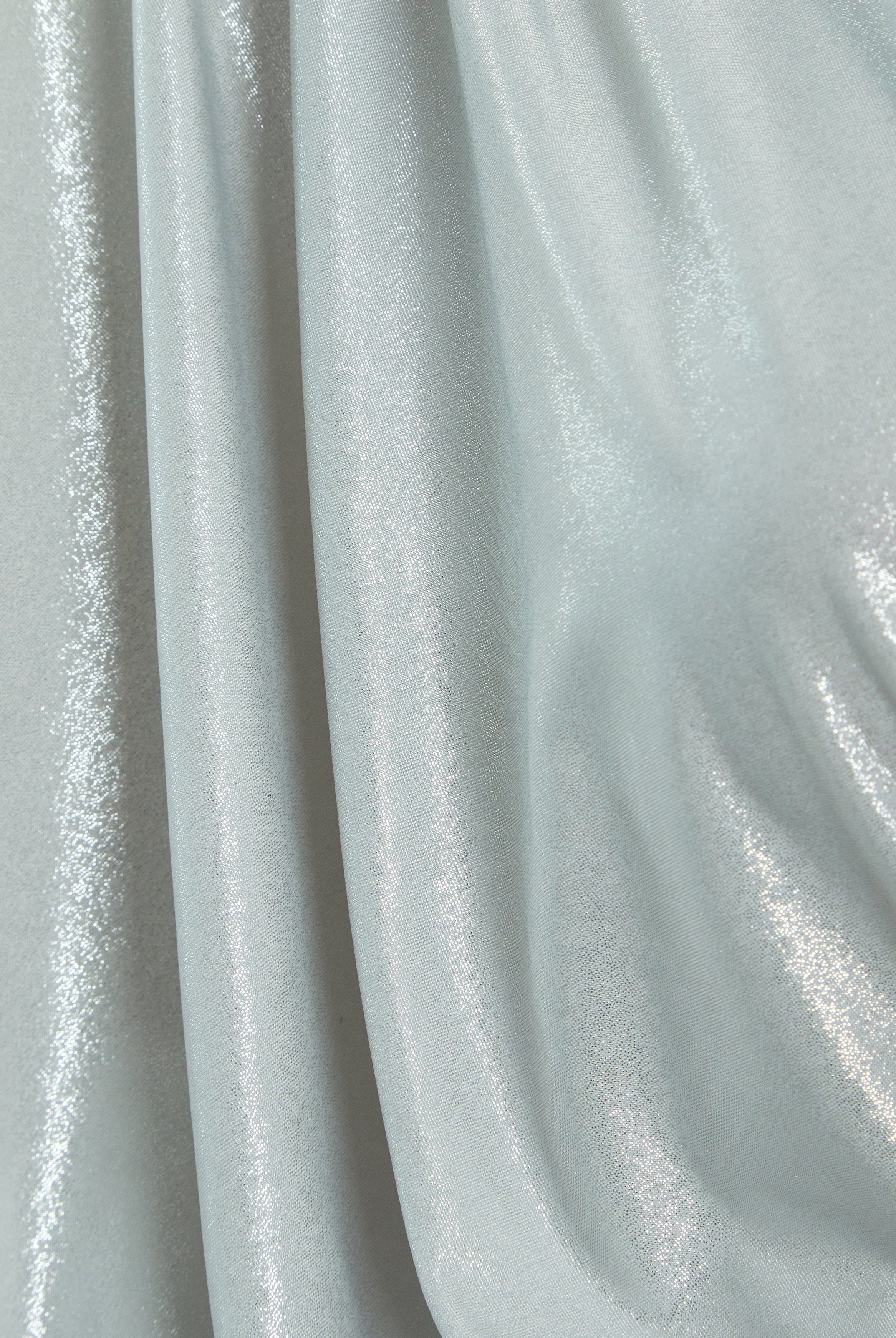 A close-up of silver metallic fabric with a shiny, reflective surface and soft folds—ideal for creating the Sarvin Batwing Sleeve Midi Dress, perfect for a show-stopping party look.