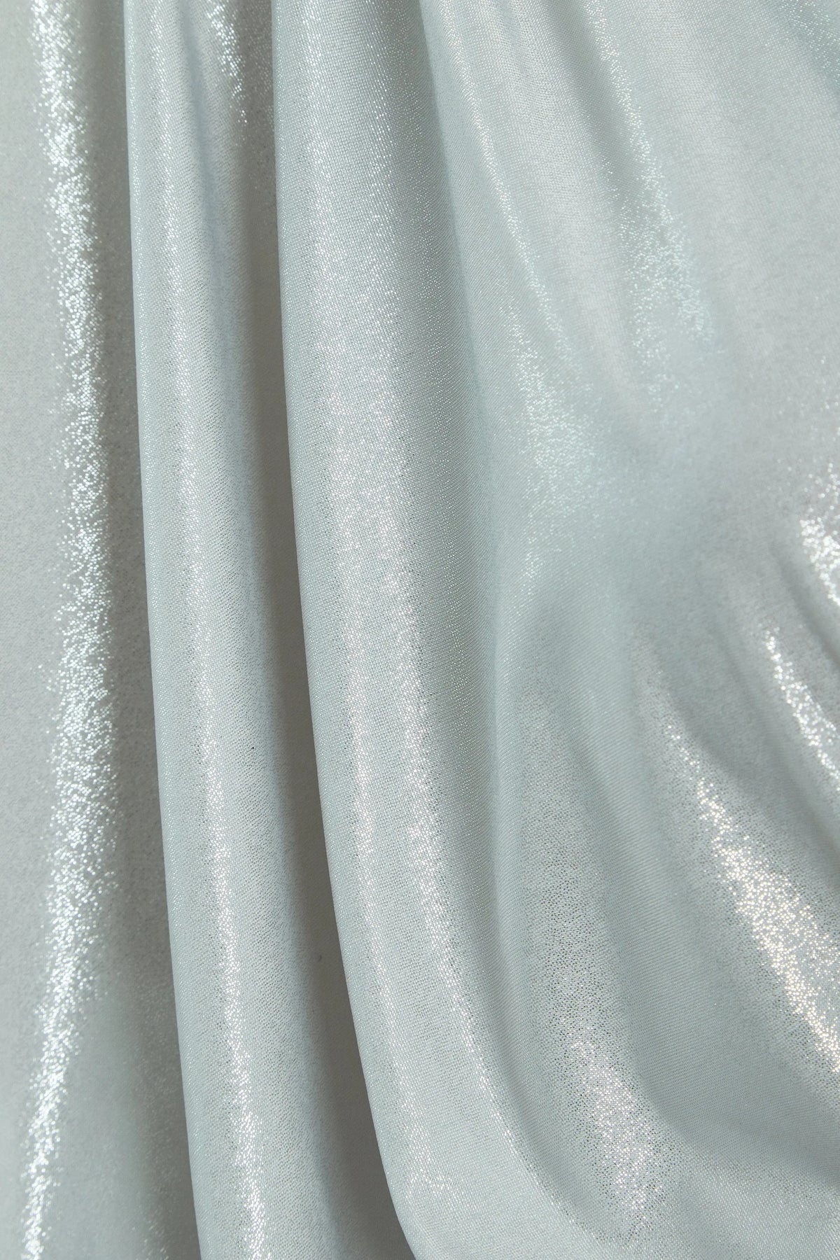 A close-up of silver metallic fabric with a shiny, reflective surface and soft folds—ideal for creating the Sarvin Batwing Sleeve Midi Dress, perfect for a show-stopping party look.