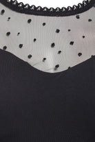 Close-up of the Sarvin Long-Sleeve Mesh Bodysuit, showcasing sheer black mesh with small polka dots and a delicate lace-trimmed neckline.