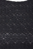 Close-up of the Black Twisted Backless Dress by Sarvin, highlighting its geometric black lace with open and solid sections for a textured, intricate look. The semi-sheer lace adds depth, making it ideal for a standout style.