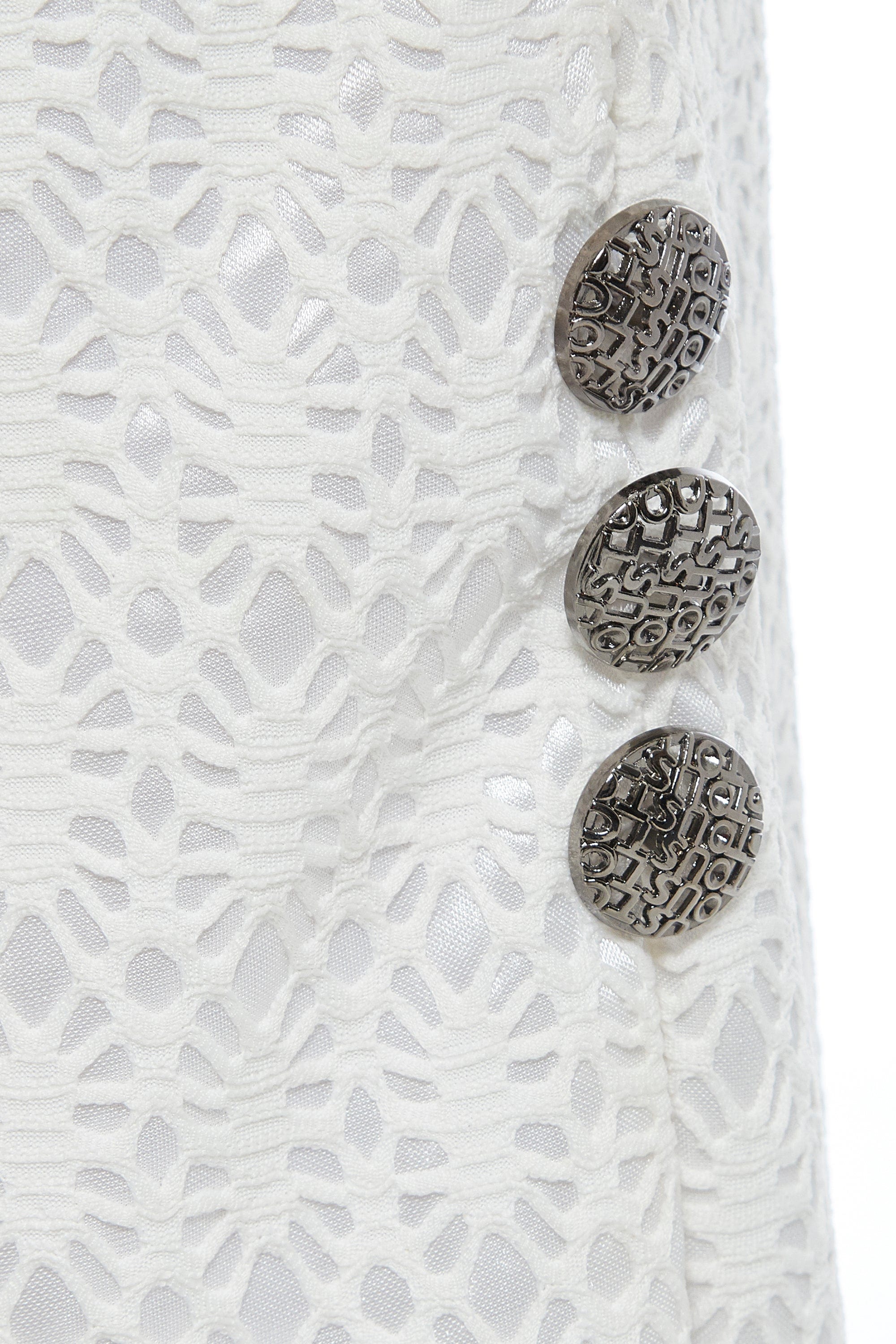 Close-up of Sarvin's White Bodycon Lace Skirt, handmade in the UK with a high waist, featuring three textured silver buttons on the right over floral lace and a shiny white lining.