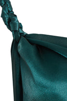 Close-up of Sarvin's Emerald Green Maxi Dress fabric, showcasing its shiny, dark green satin texture with a smooth, slightly reflective finish, reminiscent of an elegant gown.