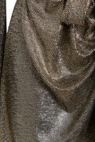 Close-up of the Sarvin Long Sleeve Sequin Wrap Dress showcases its metallic, textured fabric in gold. The densely woven sequins and gathered folds create a shiny, reflective effect ideal for evening events under bright lights.