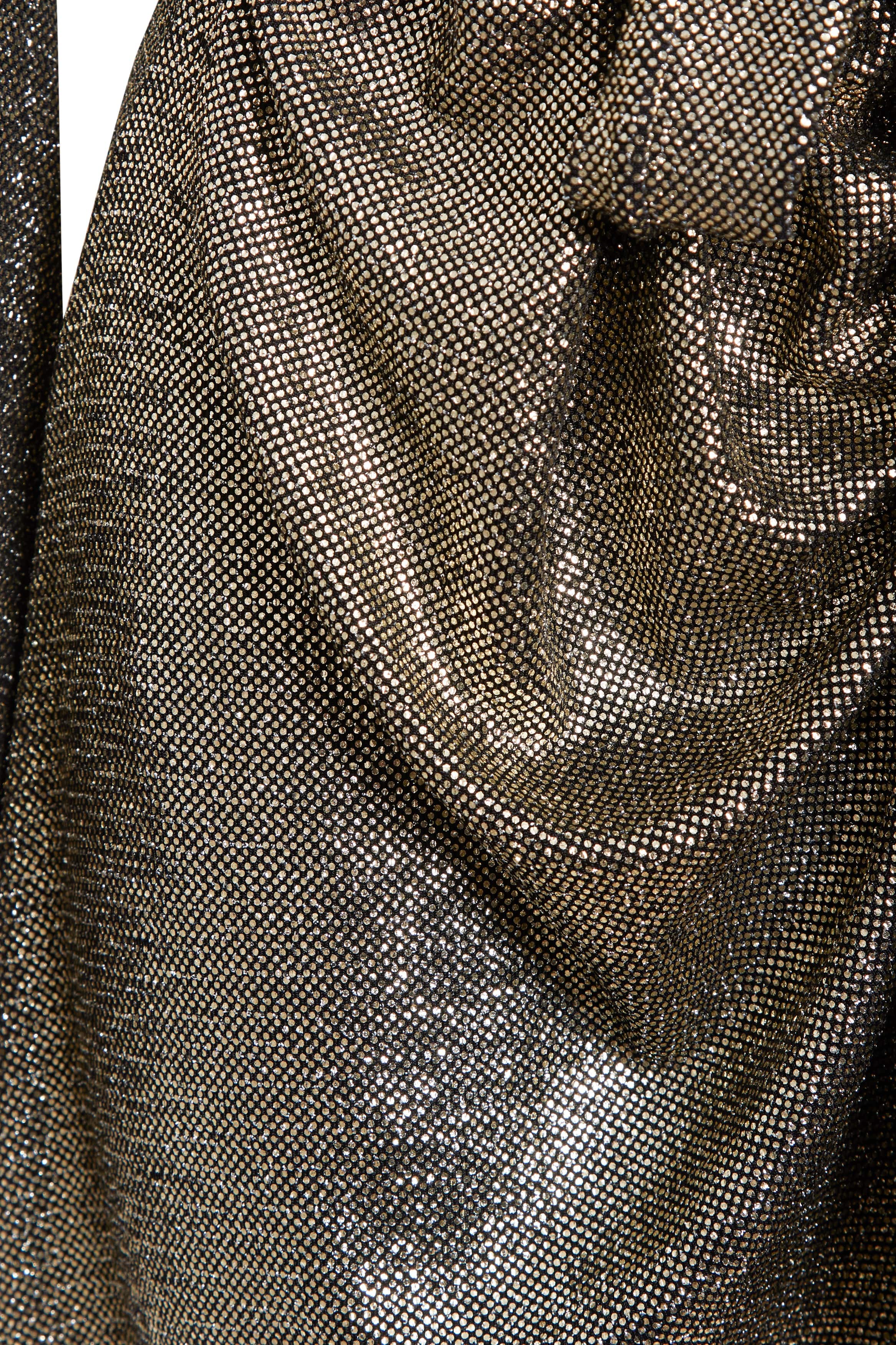 Close-up of the Sarvin Long Sleeve Sequin Wrap Dress showcases its metallic, textured fabric in gold. The densely woven sequins and gathered folds create a shiny, reflective effect ideal for evening events under bright lights.