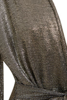 Close-up of Sarvin's Long Sleeve Sequin Wrap Dress, featuring metallic, shimmering fabric with a fine mesh pattern draped at the waist. The material reflects light beautifully, creating a textured effect perfect for evening wear.