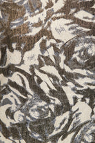 A close-up of Sarvin's Puff Shoulder Mini Dress shows its textured golden floral jacquard fabric with an abstract cream, brown, and gray pattern, slight sheen, and visible woven threads.