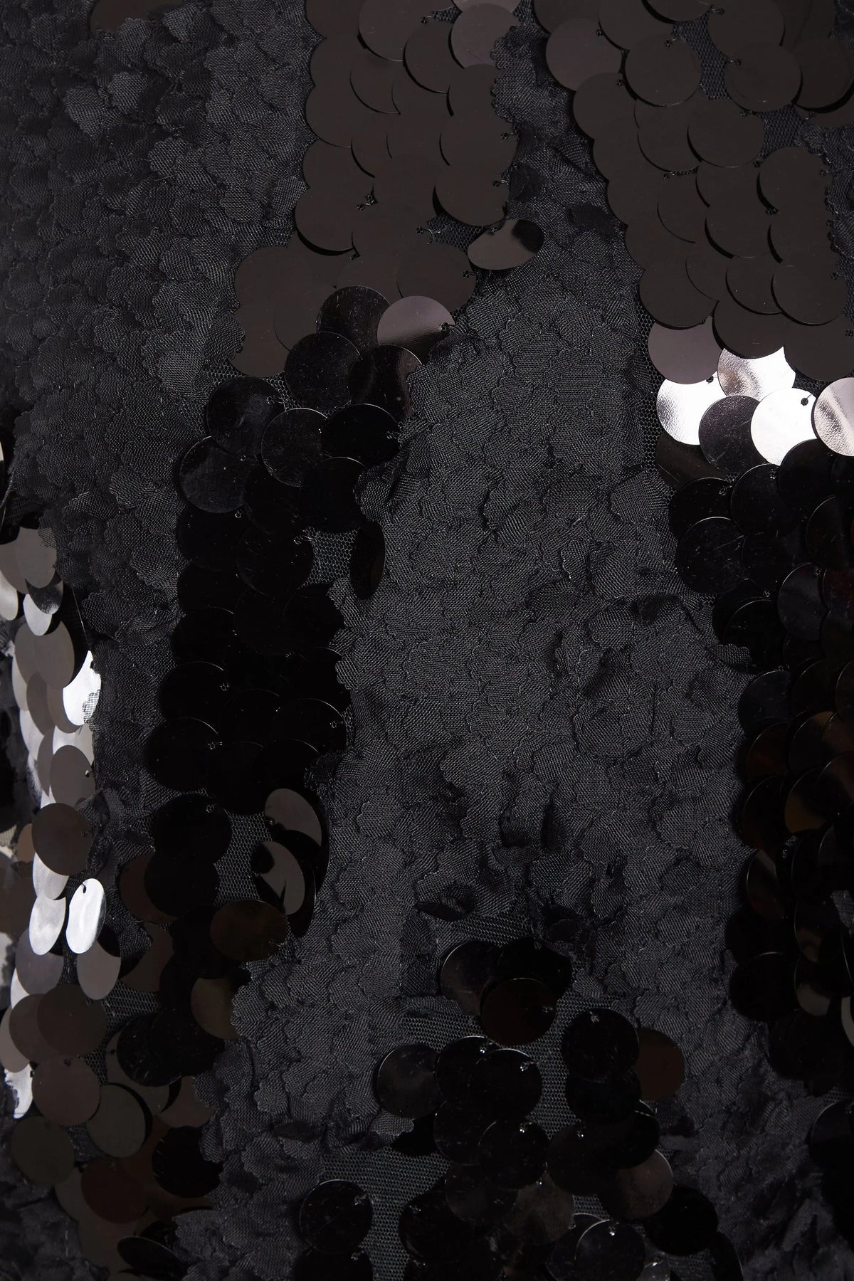Close-up of the Sarvin Black Backless Sequin Mini Dress, featuring shiny round black sequins with an uneven texture from overlapping layers—reflecting light for a glamorous party-ready look.