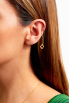 Close-up of a woman's ear wearing Sarvin's Clover Shape 18K Gold Threader Earrings, featuring a delicate clover charm; her straight brown hair and green top are partially visible.