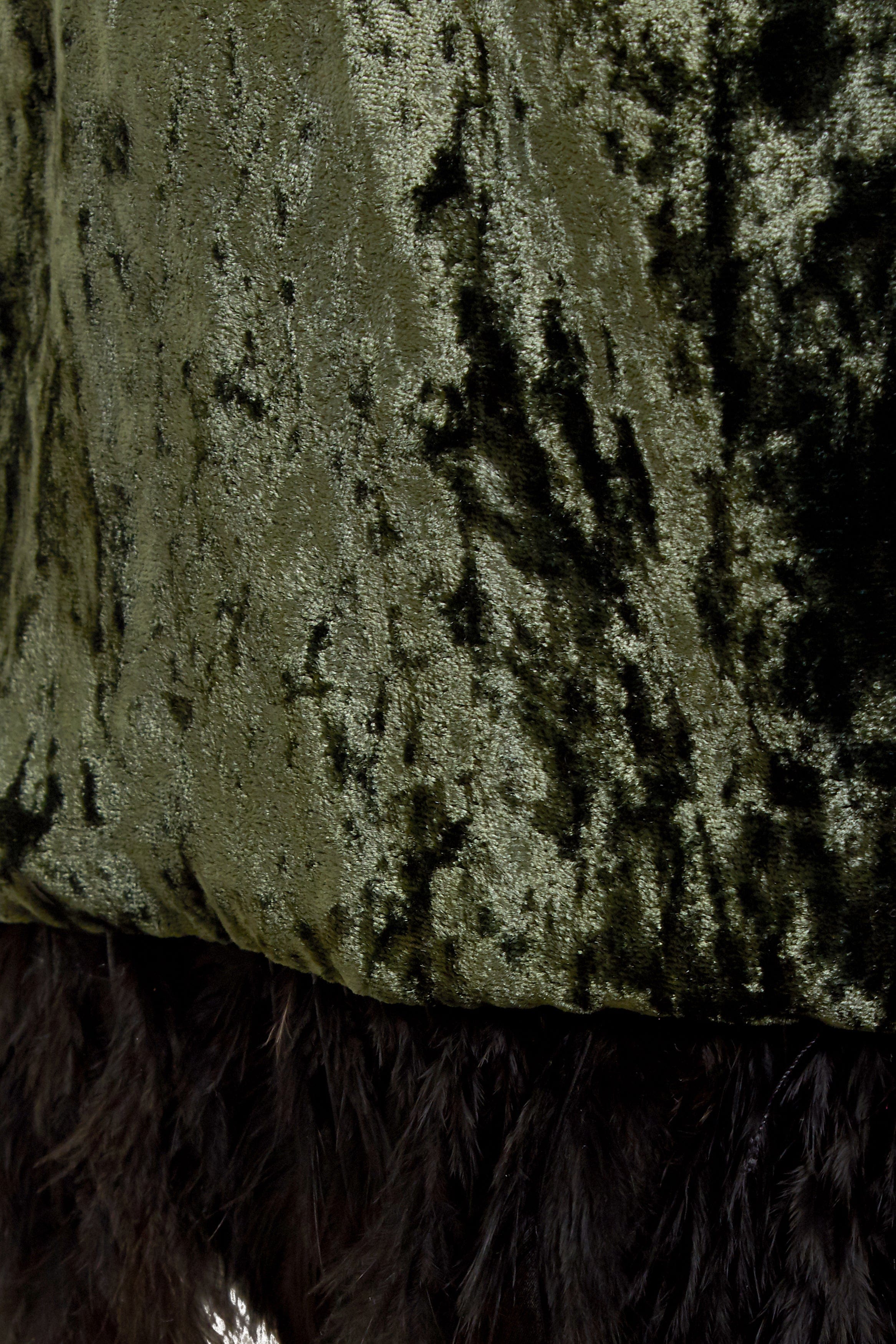 Close-up of the Sarvin Silk Velvet Feather Trim Dress in forest green, featuring a shiny, textured silk velvet fabric and a black ostrich feather hem.