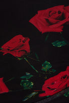 Close-up of black fabric with large red roses and green leaves, showing detailed texture—ideal for a UK-made Ruched Bodycon Mini Dress by Sarvin.