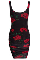 The Sarvin Ruched Bodycon Mini Dress is a sleeveless, form-fitting black mini dress with red rose and green leaf print, plus side ruching.