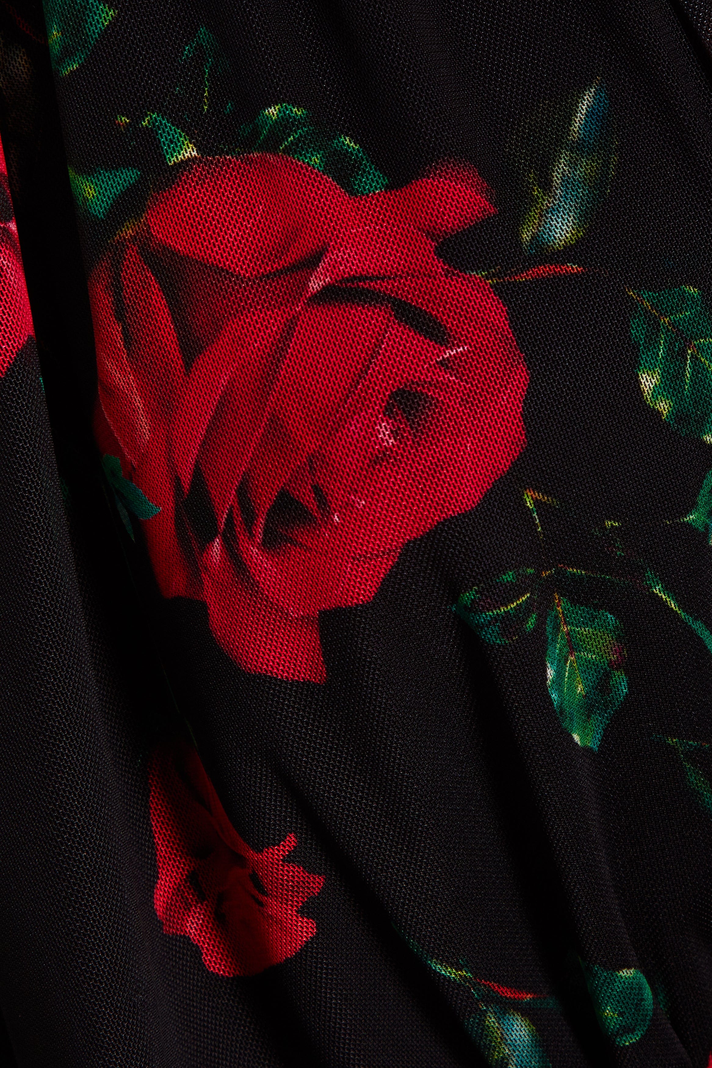 A close-up of Sarvin's Ruched Bodycon Mini Dress fabric in black, featuring a red rose floral print with green leaves, highlighting its textured weave—ideal for this standout piece.