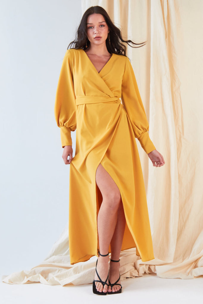 Brunette long haired female wearing yellow mustard long sleeved wrap dress
