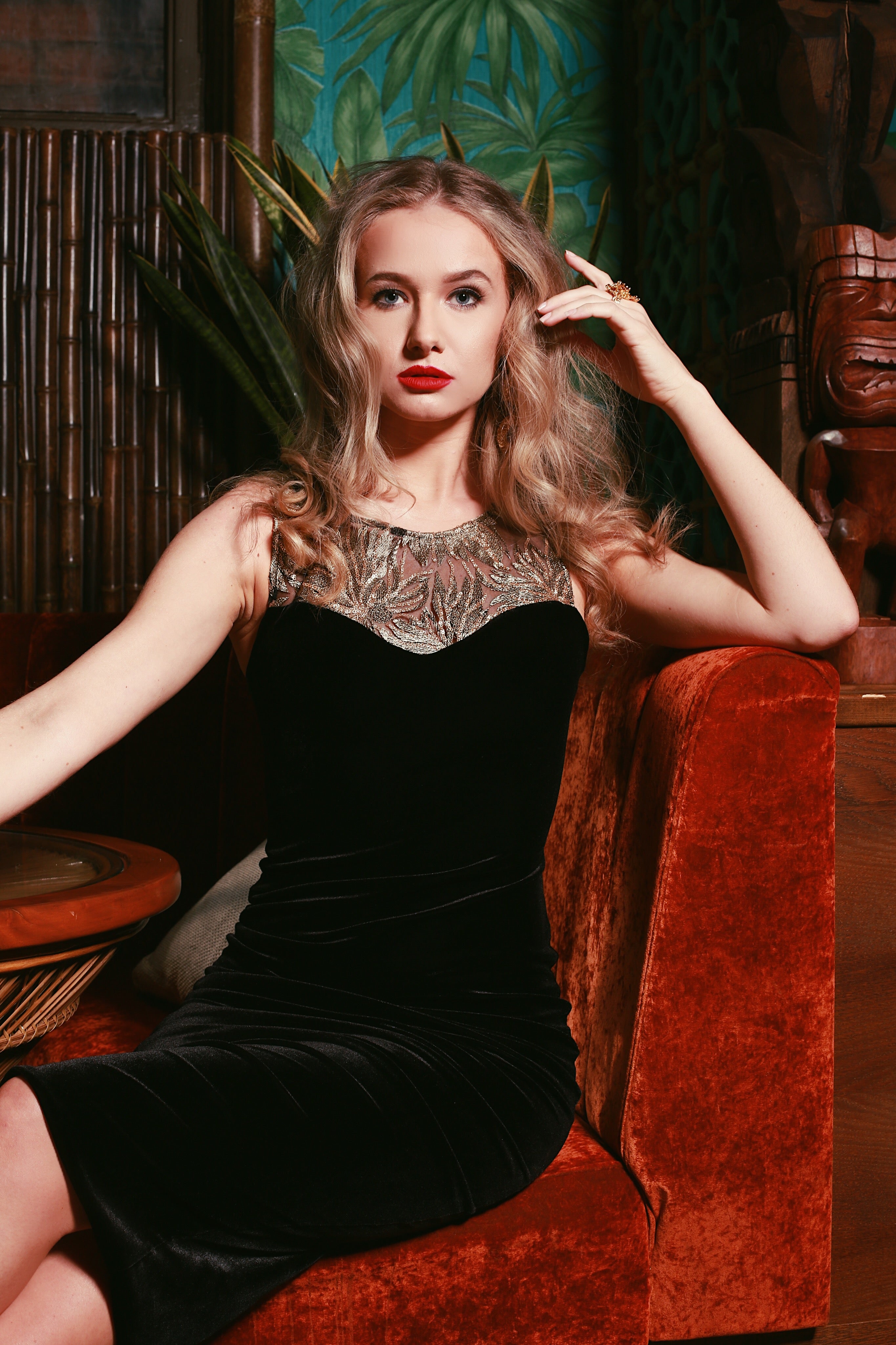 a woman in a black dress sitting on a red couch.