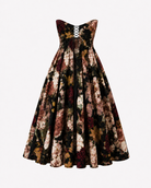The Sarvin Golshifteh Floral Corset Midi Dress is a strapless A-line dress with a dark, muted floral pattern. It features a fitted bodice with a front lace-up detail and a full, pleated midi skirt. The dress is displayed against a plain white background.