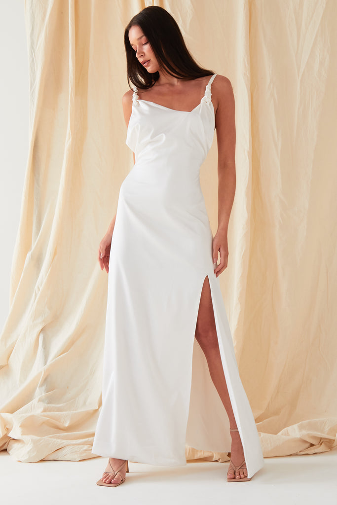 The model is wearing a Sarvin White Asymmetric Maxi Dress with a slit.