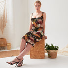 A woman is sitting on a wooden box in a Sarvin Sleeveless Floral Bodycon Dress.