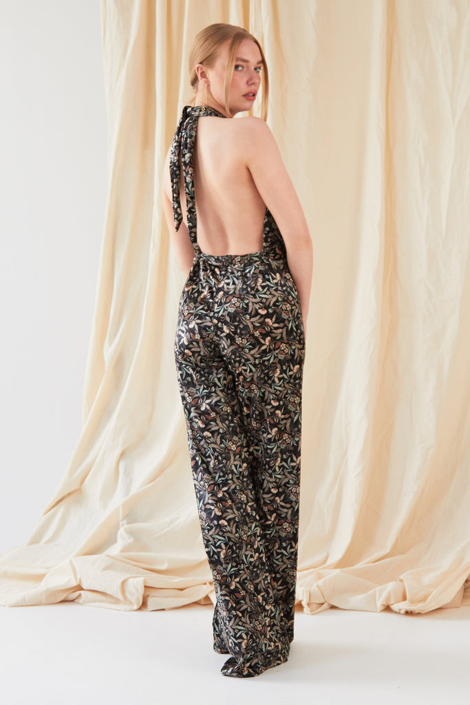 The back view of a woman wearing a Sarvin Floral Velvet Backless Jumpsuit.