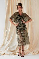 A woman is posing for a photo in a Sarvin Embroidered Flutter Sleeve Dress.