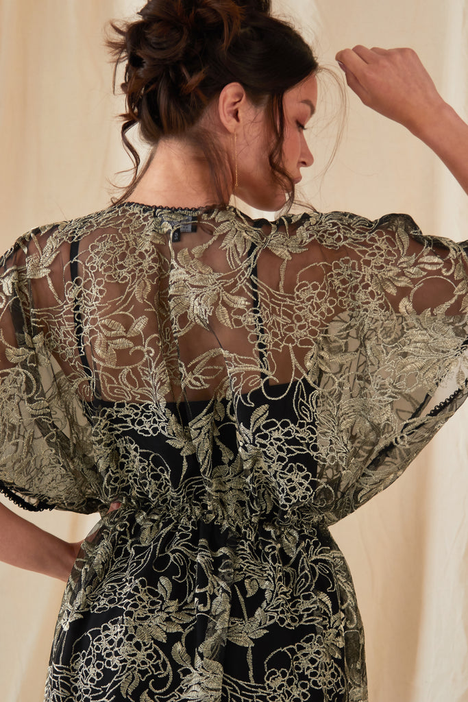 the back of a woman wearing an Embroidered Flutter Sleeve Dress by Sarvin.