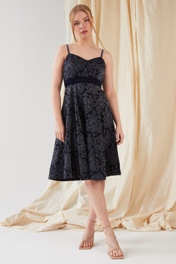 The model is wearing a Sarvin Jacquard Fit And Flare Dress with lace and straps.