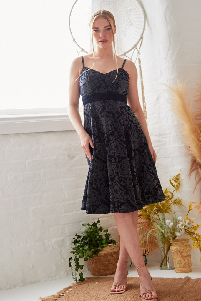a woman in a Sarvin Jacquard Fit And Flare Dress standing in front of a window.