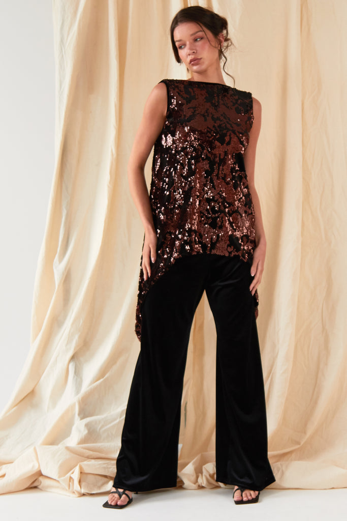 The model is wearing a Sarvin sequin top and Sarvin Wide Leg Velvet Trousers.