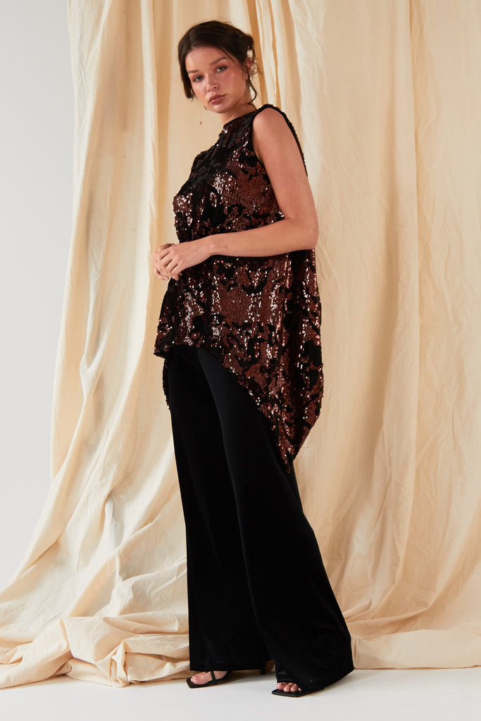 The model is wearing a black sequined top and Sarvin Wide Leg Velvet Trousers.
