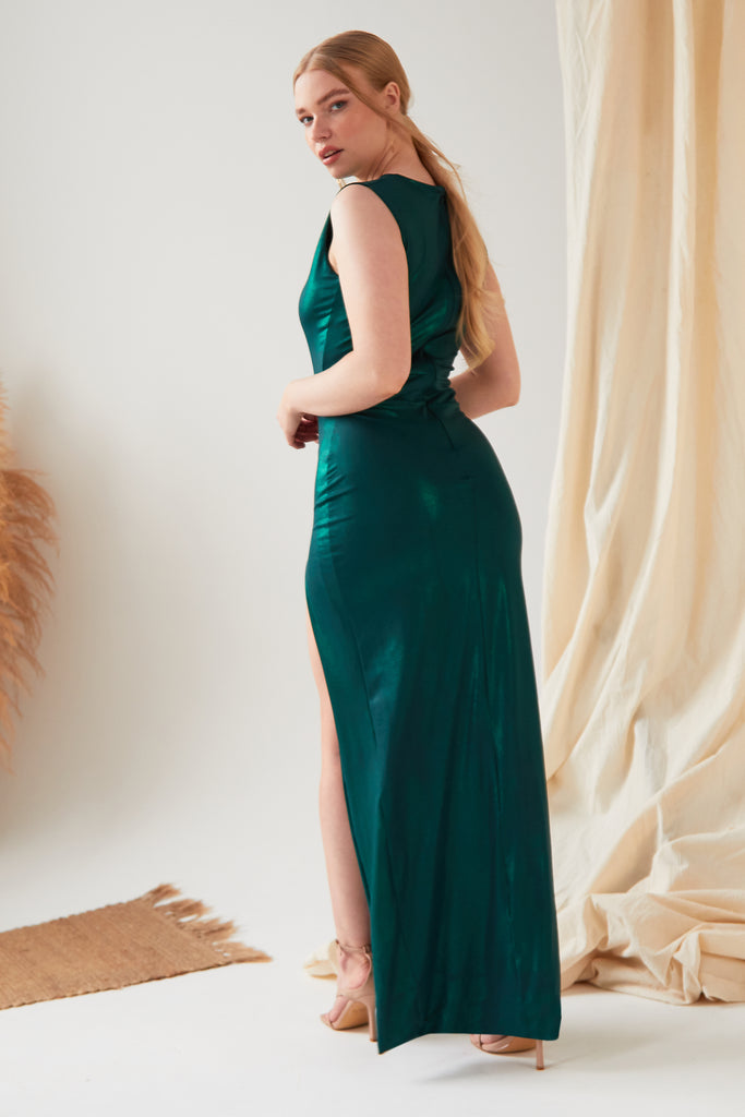 The model is wearing a Sarvin Green Cut Out Side Dress with a slit.