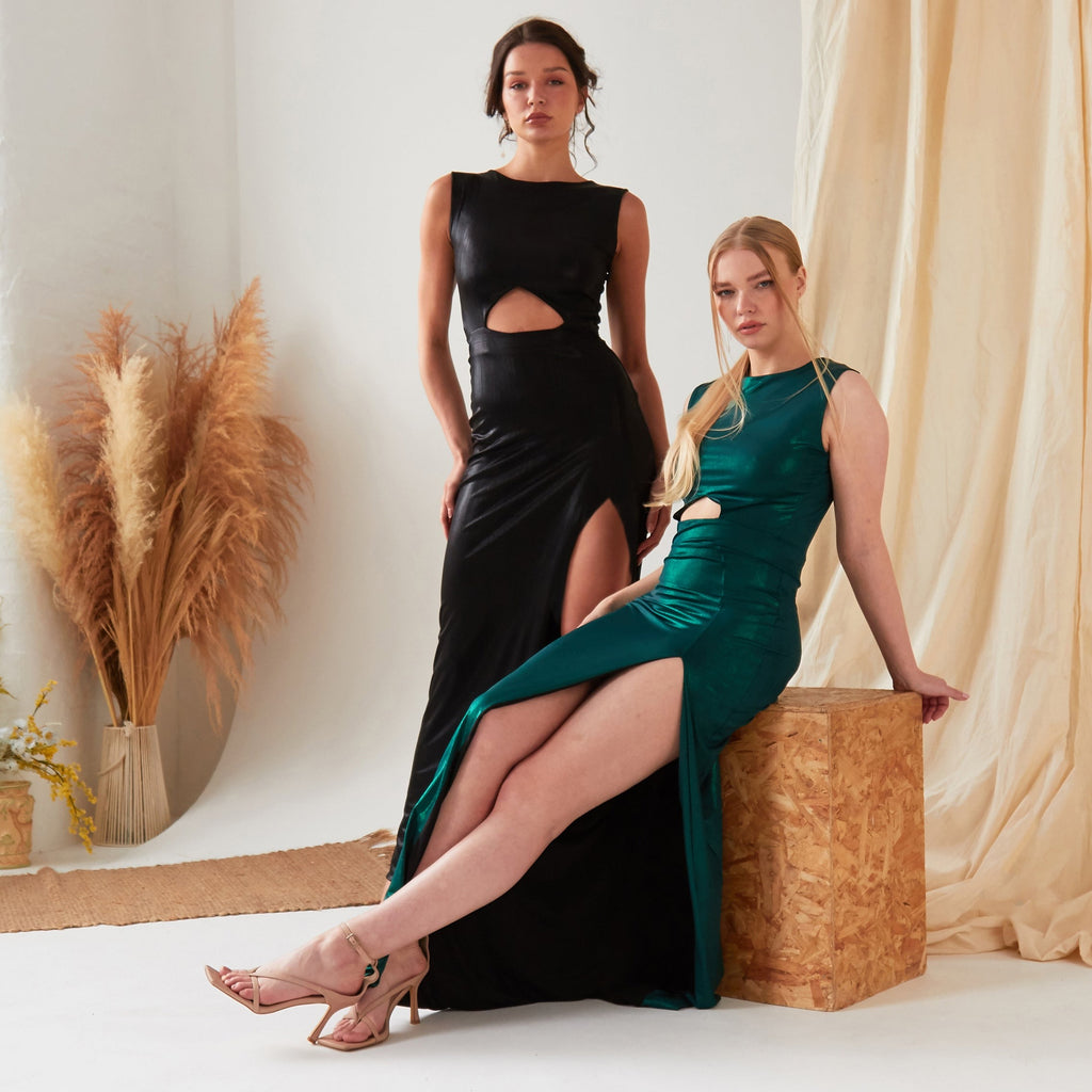 Two women in Sarvin's Green Cut Out Side Dresses posing in front of a wooden box.