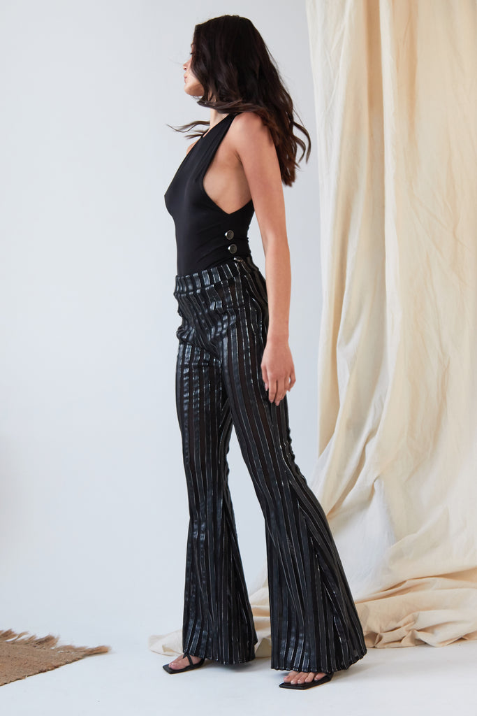 a woman wearing Sarvin's Flare Trousers In Metallic Stripe and a black top.