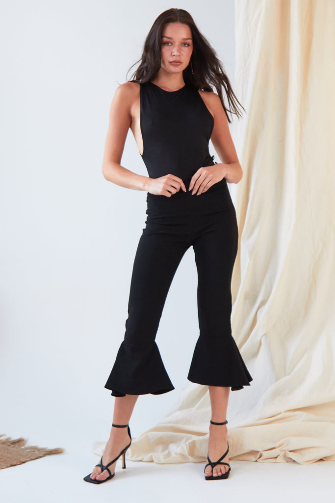 The model is wearing Sarvin's Black Frill Hem Trousers.