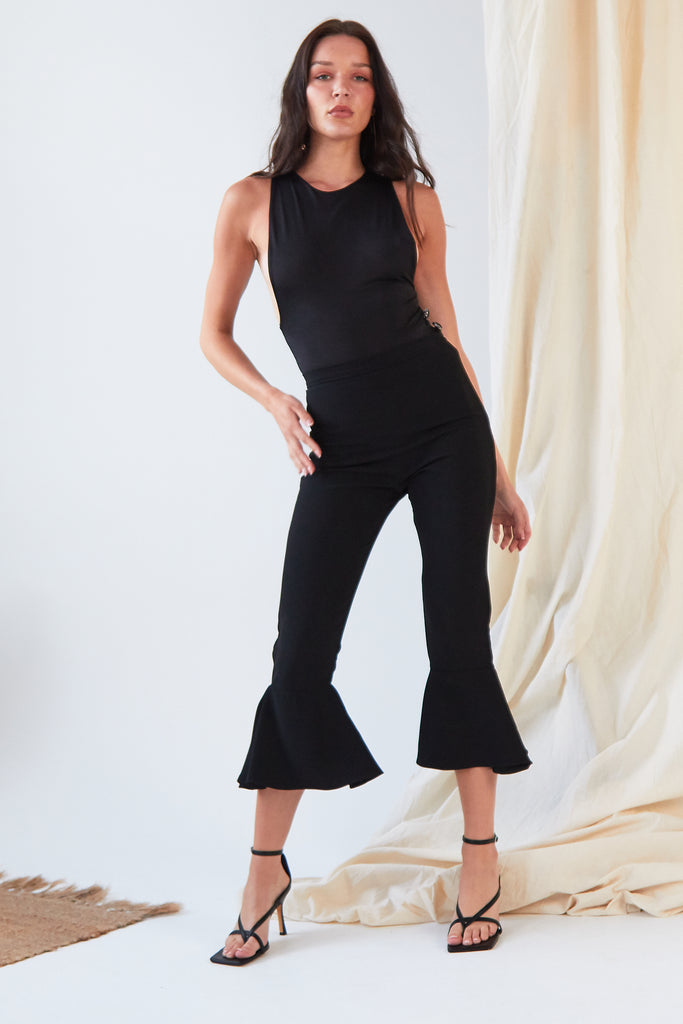 the model is wearing a Sarvin black crop top and Sarvin flared pants.