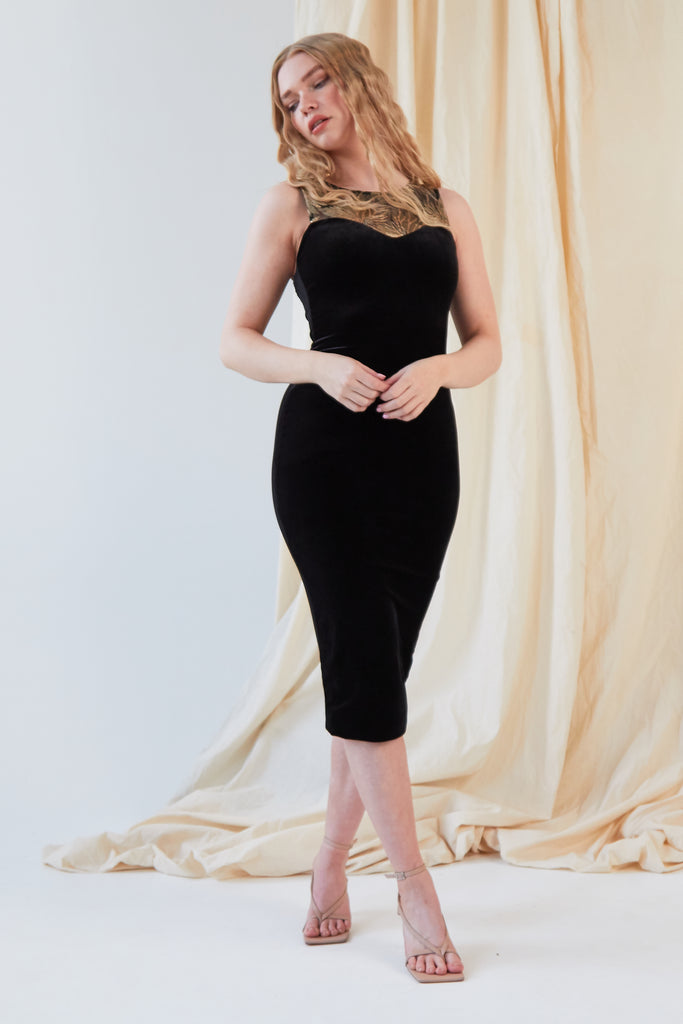 A woman in a black velvet Sarvin Sweetheart Neckline Dress posing for a photo.