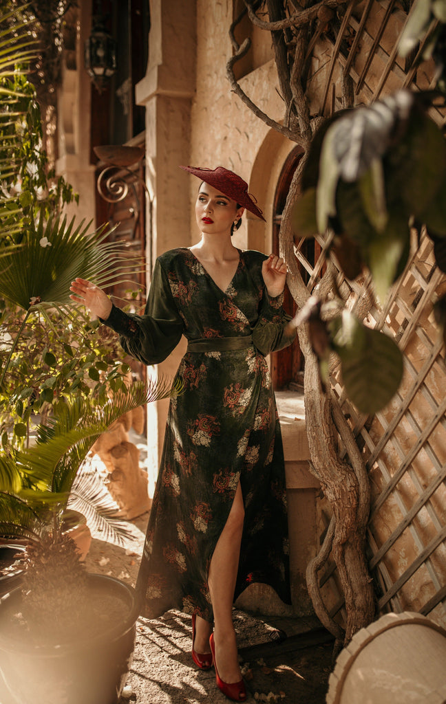 a woman in a Sarvin Long Sleeve Wrap Dress standing in front of a potted plant.