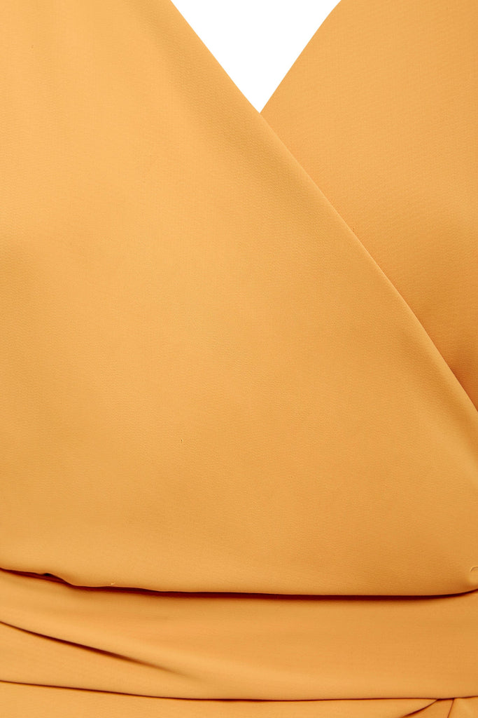 A close up of a Sarvin Mustard Wrap Dress with a v-neck.